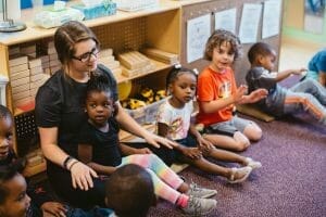 Teacher sits on the floor with children