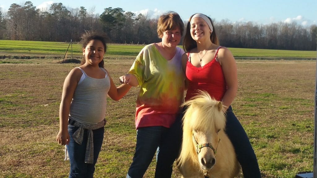 Kids posing together with a pony